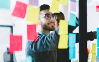 A Gen-Zer stands in front of a wall of sticky notes.